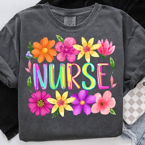 May include: Dark gray sweatshirt with the word "NURSE" in rainbow-colored letters, surrounded by colorful flowers in shades of orange, pink, yellow, and purple. The sweatshirt is a comfortable, casual style.