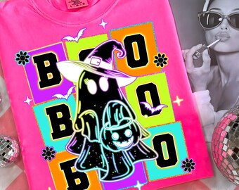 Puede incluir: Una camiseta rosa brillante con cuello redondo y un diseño de Halloween. El diseño presenta la palabra "BOO" en letras negras grandes sobre cuadrados coloridos, un fantasma con un sombrero de bruja y una calabaza.