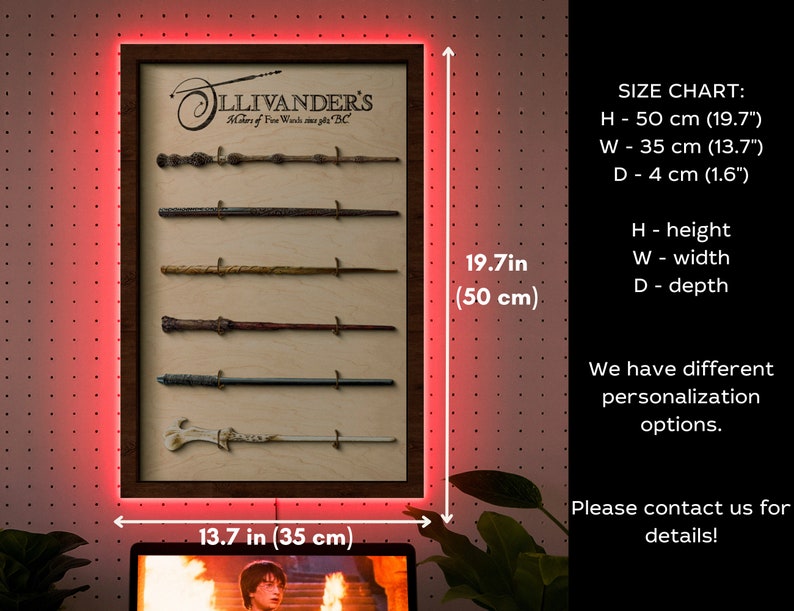 May include: A wooden frame with a light wood background and a dark wood border. The frame is displaying a collection of six wands, each with a different design. The frame is 50 cm tall and 35 cm wide. The text "Ollivander's Makers of Fine Wands since 382 BC" is printed on the frame. The frame is illuminated with red LED lights.