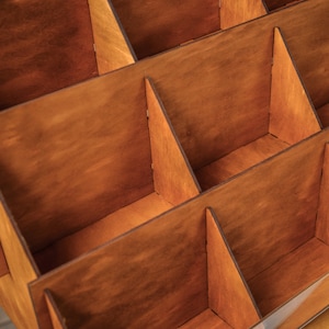 May include: A wooden display stand with multiple compartments, perfect for organizing and showcasing small items. The stand is made of natural wood with a warm brown finish.