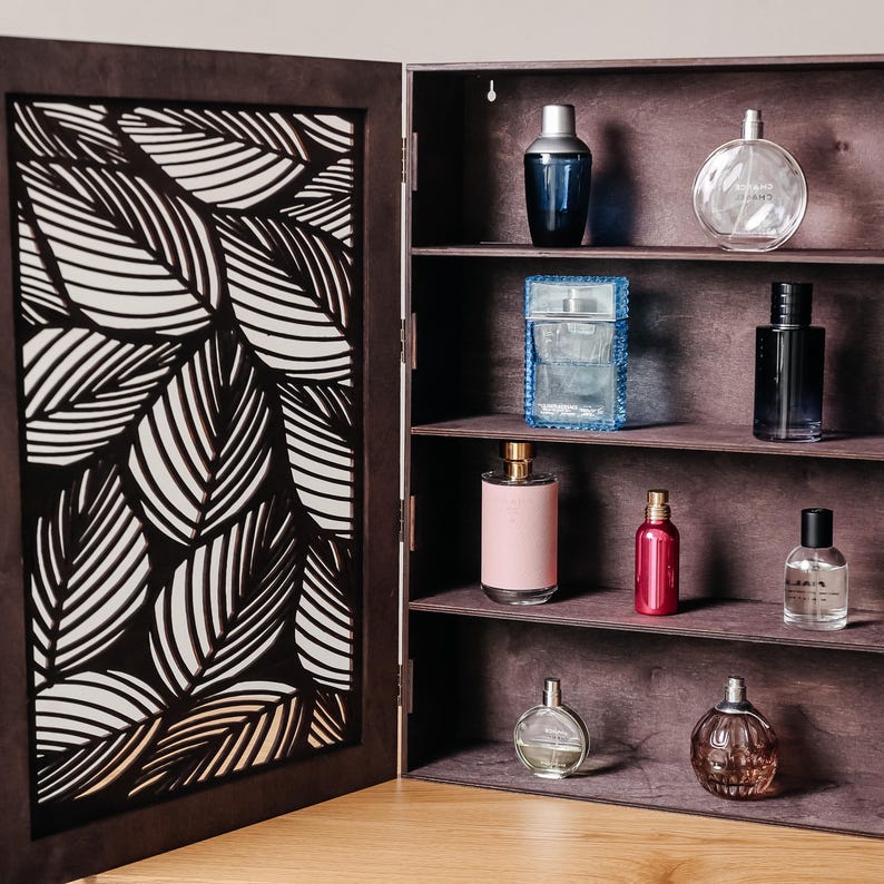 May include: A dark brown wooden cabinet with a patterned door and four shelves. The shelves are filled with various glass bottles of perfume and cologne.