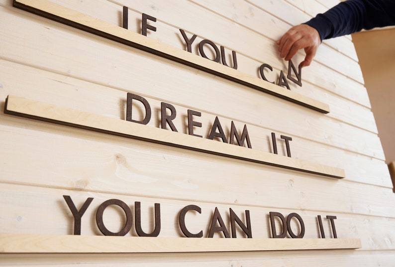 May include: Wooden wall decor with the phrase "If you can dream it, you can do it" in brown letters.
