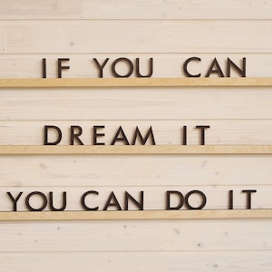 May include: A wooden wall with three shelves, each displaying a motivational phrase in black letters. The top shelf reads "IF YOU CAN", the middle shelf reads "DREAM IT", and the bottom shelf reads "YOU CAN DO IT".