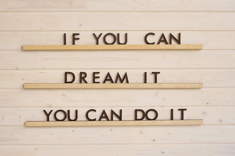 May include: A wooden wall with three shelves, each displaying a motivational phrase in black letters. The top shelf reads "IF YOU CAN", the middle shelf reads "DREAM IT", and the bottom shelf reads "YOU CAN DO IT".