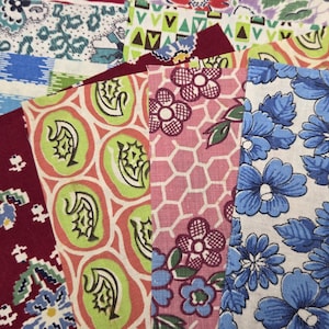 May include: A collection of fabric swatches featuring various patterns including blue flowers, pink honeycomb with floral motifs, green and orange abstract shapes, and a deep red background with small white and green floral designs.