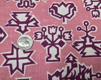 May include: A pink fabric featuring a repeating pattern of dark purple geometric floral and star-like motifs. A silver-colored United States dime coin is placed on the fabric to provide a sense of scale for the printed design elements.