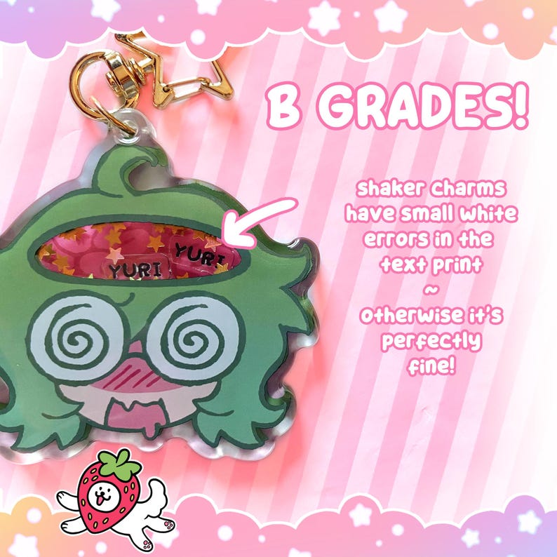May include: A green cartoon character shaker charm with a gold star-shaped clasp. The charm has a pink and gold glitter interior and the text "YURI". The text "B GRADES!" is also visible.