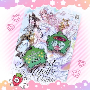 May include: Two anime-style keychains with gold star accents and a manga book. One keychain is green with the text "NO THOUGHTS ONLY YURI". The other is green with a dizzy face. The manga features two women in white dresses.