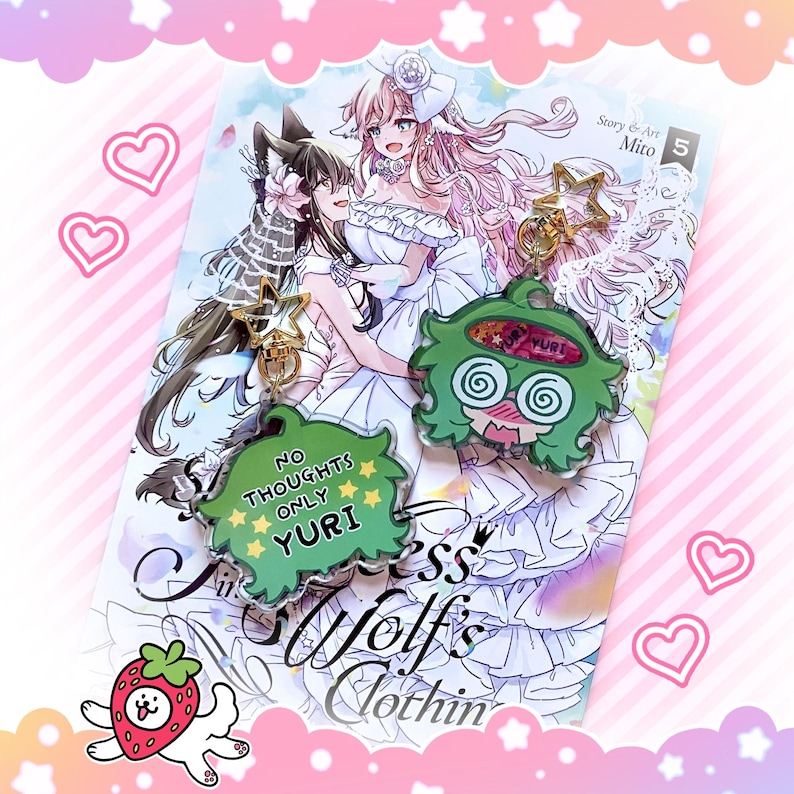 May include: Two anime-style keychains with gold star accents and a manga book. One keychain is green with the text "NO THOUGHTS ONLY YURI". The other is green with a dizzy face. The manga features two women in white dresses.