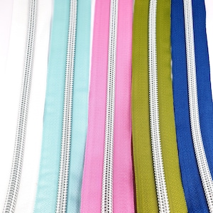 May include: Five zipper tapes with silver metal teeth. The tapes are white, light blue, pink, olive green, and navy blue.