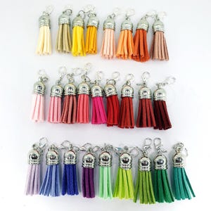 May include: Assortment of 30 colourful tassel keychains with silver metal clasps. The tassels are made of soft, fuzzy material and come in a variety of colours, including pink, red, blue, green, yellow, and orange.