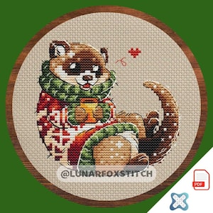 May include: A cross-stitch design of a brown and white otter wearing a green scarf and a red sweater, holding a mug. The otter is inside a wooden embroidery hoop. The text "@LUNARFOXSTITCH" is at the bottom.