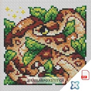 May include: A cross-stitch pattern featuring a detailed design of a creature with brown, tan, and green hues, surrounded by leaves and stars. The text "@LUNARFOXSTITCH" is visible at the bottom. A PDF icon is in the lower right corner.