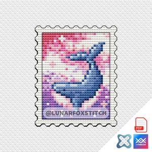 Pode incluir: Um padrão de ponto cruz com uma baleia azul saltando para fora da água com um fundo rosa e branco. O padrão é emoldurado em uma forma de selo branco com uma borda preta e o texto "@LUNARFOXSTITCH".