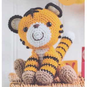 May include: A crocheted tiger toy with black and orange stripes, sitting on a wicker basket. The toy has a white face with black eyes and a brown nose.
