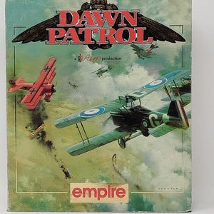 May include: A rectangular board game box cover titled Dawn Patrol, featuring a painted aerial combat scene with a bright red triplane and a green biplane flying through a cloudy sky. The text Rowan production and empire are printed on the box.