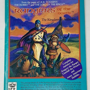 Puede incluir: Una caja de juego vintage titulada "Rangers of the North" con ilustraciones de personajes de El Hobbit y El Señor de los Anillos de J.R.R. Tolkien. La caja presenta un borde azul y el texto "The Kingdom of Arthedain".