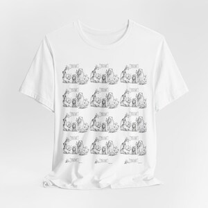 Op de afbeelding: Wit T-shirt met een herhaalde zwart-wit cartoon illustratie van verschillende dieren, waaronder olifanten, giraffen en leeuwen. Elke dierengroep heeft een tekstballon met tekst. Het shirt is gemaakt van een zachte, lichte stof.