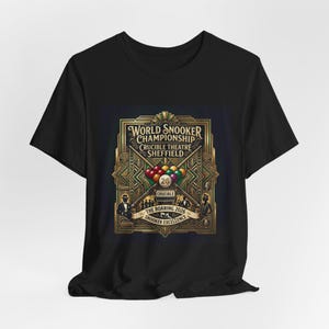 Könnte beinhalten: Schwarzes T-Shirt mit goldener und bronzefarbener Grafik für die Snooker-Weltmeisterschaft im Crucible Theatre, Sheffield. Das Design umfasst Snooker-Kugeln, gekreuzte Queues und den Text "The Roaring 2026 Snooker Excellence."