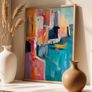 a vibrant abstract painting displayed on a white wall, with a vase of dried reeds placed to the left of the painting.