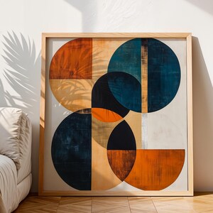 May include: A square wall art piece in a light wood frame featuring a geometric composition of overlapping circles and semicircles in deep navy blue, burnt orange, and cream tones with visible brushstroke textures on a white background.