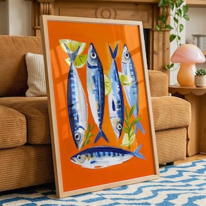 a vibrant orange framed artwork depicting a lively scene of four blue and white fish swimming together, set against a backdrop of green plants and a wooden shelf.
