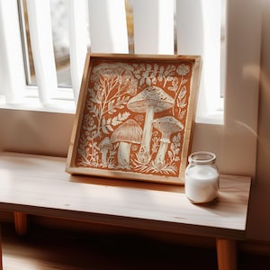Autumn mushroom art print featuring a tall central mushroom surrounded by smaller mushrooms and woodland botanicals in warm earthy tones. Detailed fall botanical illustration that captures the beauty of forest landscapes, ideal for rustic kitchens, autumn cottagecore interiors, woodland décor or seasonal gallery walls. Perfect mushroom wall art for adding warm autumn charm and woodland character to any space.