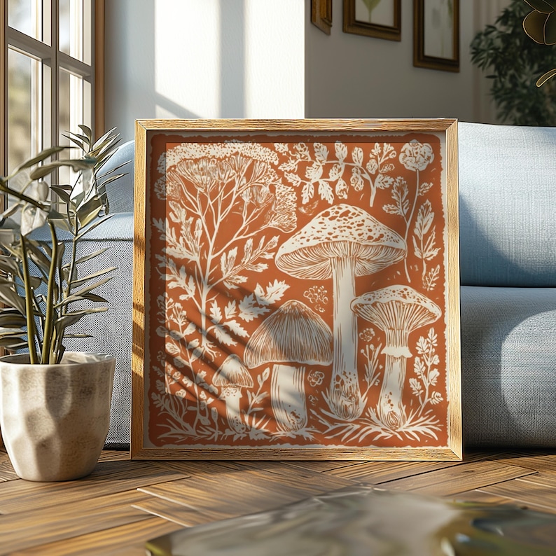a framed artwork depicting a forest scene with mushrooms, leaves, and other natural elements. The artwork is placed on a wooden floor in front of a blue couch, with a potted plant nearby.
