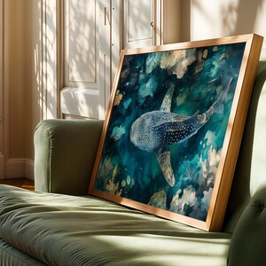 a framed painting of a whale shark swimming in the ocean, displayed on a green couch in a room with sunlight streaming in through a window.