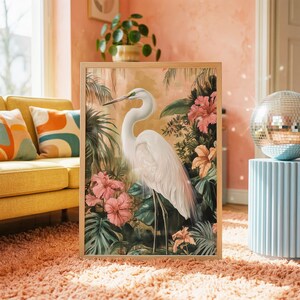 a large framed painting of a white crane standing amidst a tropical garden scene, with pink and orange flowers surrounding it.