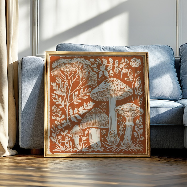 a framed artwork depicting a whimsical scene of mushrooms and plants, placed on a wooden floor in front of a blue couch.