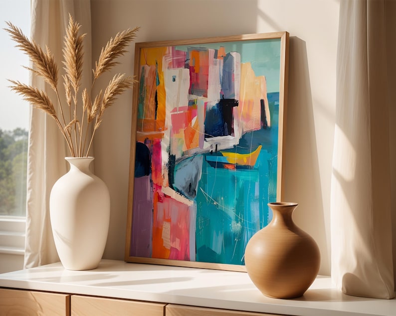 a vibrant abstract painting displayed on a white wall, with a vase of dried reeds placed to the left of the painting.