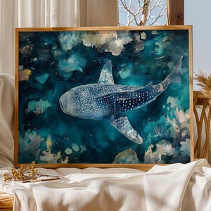 a large framed painting of a whale shark swimming in the ocean, with a wooden frame and a white cloth on a table.