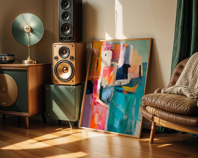 a modern living room with a large abstract painting on the wall, a brown leather chair, a wooden side table with a lamp, and a stack of speakers.