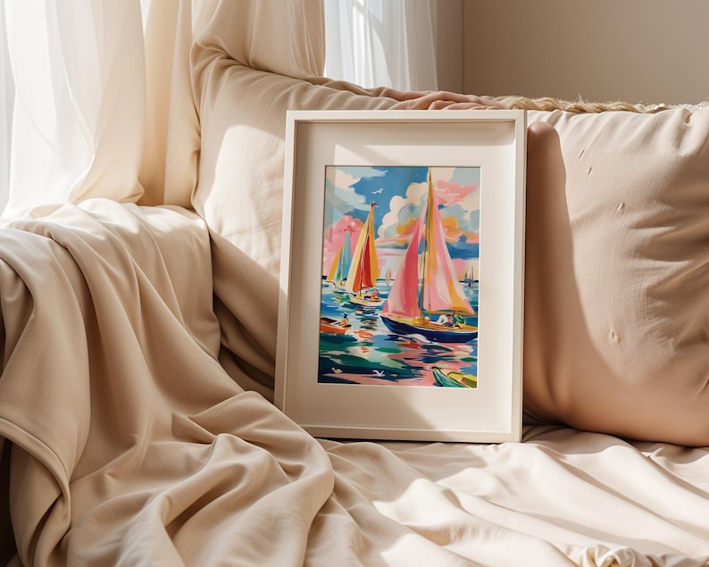 A framed painting of colorful sailboats is displayed on a beige couch, with a window and white curtains in the background.