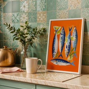 a kitchen counter with a framed painting of fish, a teapot, a white mug, and a vase of greenery.