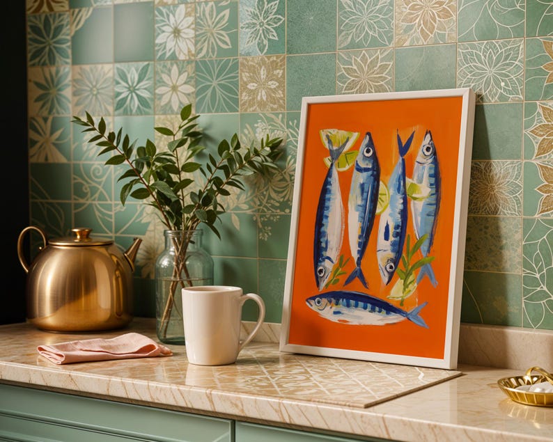 a kitchen counter with a framed painting of fish, a teapot, a white mug, and a vase of greenery.