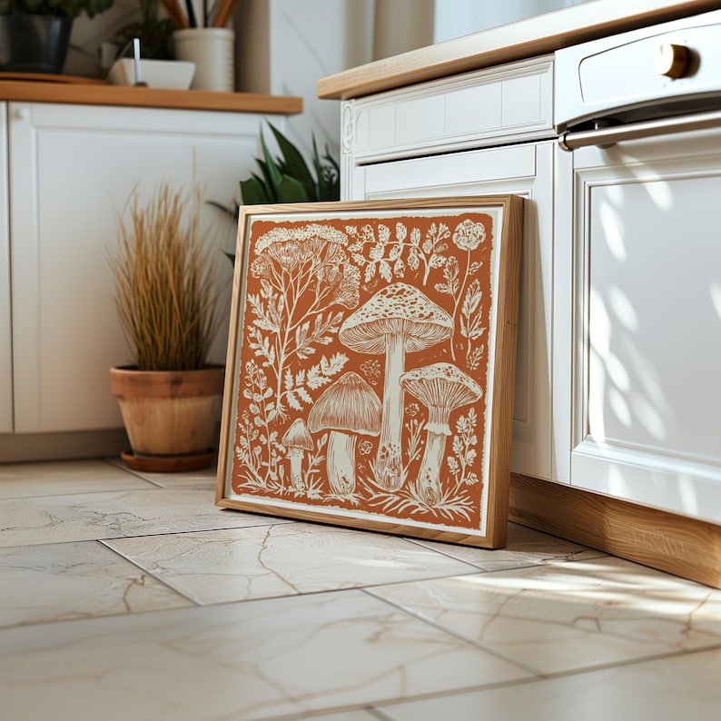 Autumn mushroom art print featuring a tall central mushroom surrounded by smaller mushrooms and woodland botanicals in warm earthy tones. Detailed fall botanical illustration that captures the beauty of forest landscapes, ideal for rustic kitchens, autumn cottagecore interiors, woodland décor or seasonal gallery walls. Perfect mushroom wall art for adding warm autumn charm and woodland character to any space.