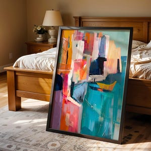 a large, colorful abstract painting displayed on a wooden floor in a bedroom.