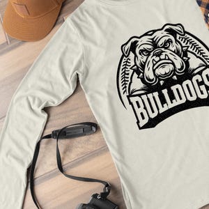 May include: A white long-sleeve shirt with a black and white graphic of a bulldog's head with the word "BULLDOGS" underneath.