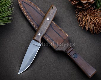 May include: A hunting knife with a wooden handle and a leather sheath. The knife has a silver blade and is set against a dark background. The text "Metal Layers" is visible.