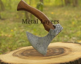 May include: A small hand axe with a wooden handle and a patterned metal blade. The axe is resting on a wooden stump. The text "Metal Layers" is visible twice in the image.