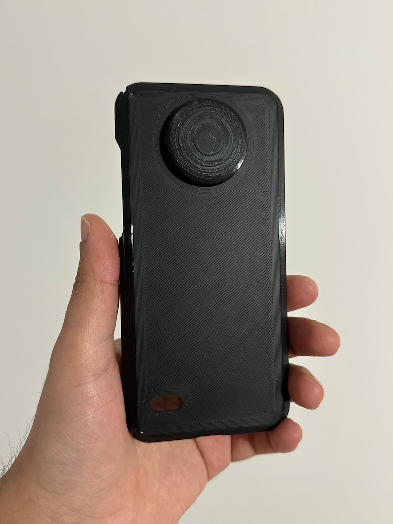 May include: A black phone case with a circular cutout on the back for a camera lens