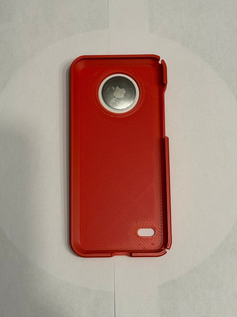May include: A red phone case with a white circle around the camera lens. The case has a textured surface.