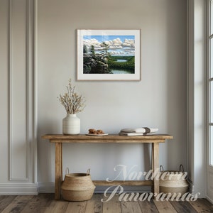 May include: A framed landscape painting of a lake and forest scene with a wooden console table and two woven baskets underneath. The painting features a blue sky with white clouds and a green forest with a lake in the distance.