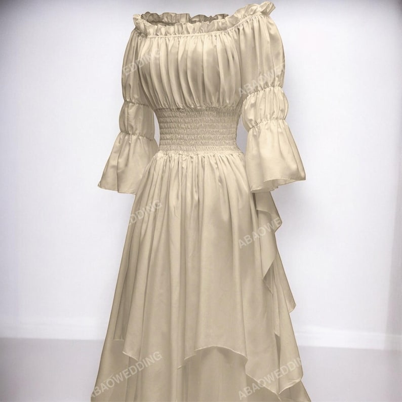 K&ouml;nnte beinhalten: Ein beiges, schulterfreies Kleid mit R&uuml;schen am Ausschnitt und einem Stufenrock. Das Kleid hat ein tailliertes Oberteil und einen lockeren, flie&szlig;enden Rock.