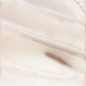 May include: Close-up of a cream-colored fabric with soft folds and subtle shadows. The fabric appears to be smooth and possibly satin or silk, with a slight sheen. The image highlights the texture and drape of the material.