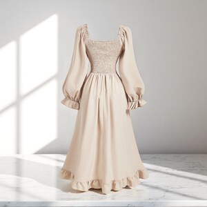 May include: A beige midi dress with a square neckline and long, voluminous sleeves. The bodice is smocked, and the skirt features a ruffled hem. The dress is made of a soft, flowing fabric.