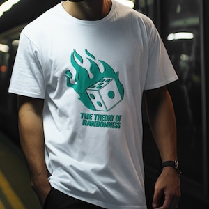 Può includere: Una persona indossa una maglietta bianca con una grafica verde e bianca di un dado in fiamme e il testo "The Theory of Randomness". La persona indossa un cappello da baseball marrone e si trova in una stazione della metropolitana.