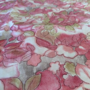 Könnte beinhalten: Nahaufnahme eines Stoffes mit floralem Muster. Das Design zeigt große, stilisierte Blumen in Rosa- und Rottönen mit grünen und braunen Akzenten. Der Hintergrund ist ein weiches Weiß.